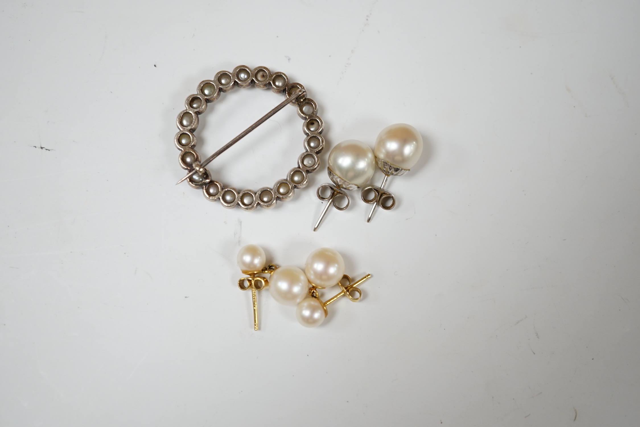 A pair of 9ct gold and two stone cultured pearl set ear studs, one pair of 9ct white metal and single stone cultured pearl set ear studs and a yellow metal and split pearl set open work brooch, 30mm.